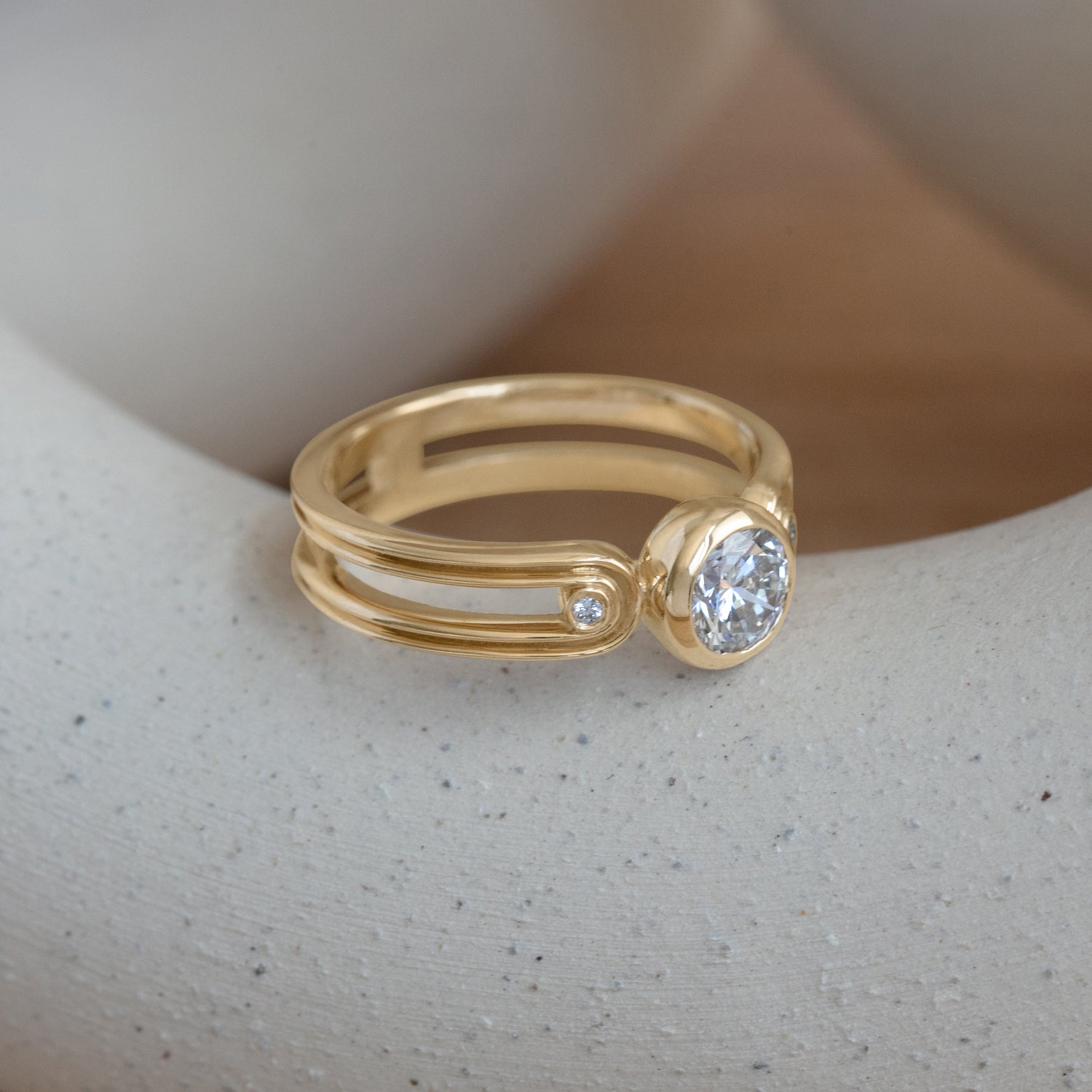 Lifestyle angled side view of Gravitational Pull Ring / Round Lab Diamond 0.75ct by Sandy Rubin on a ceramic with a blurred neutral background