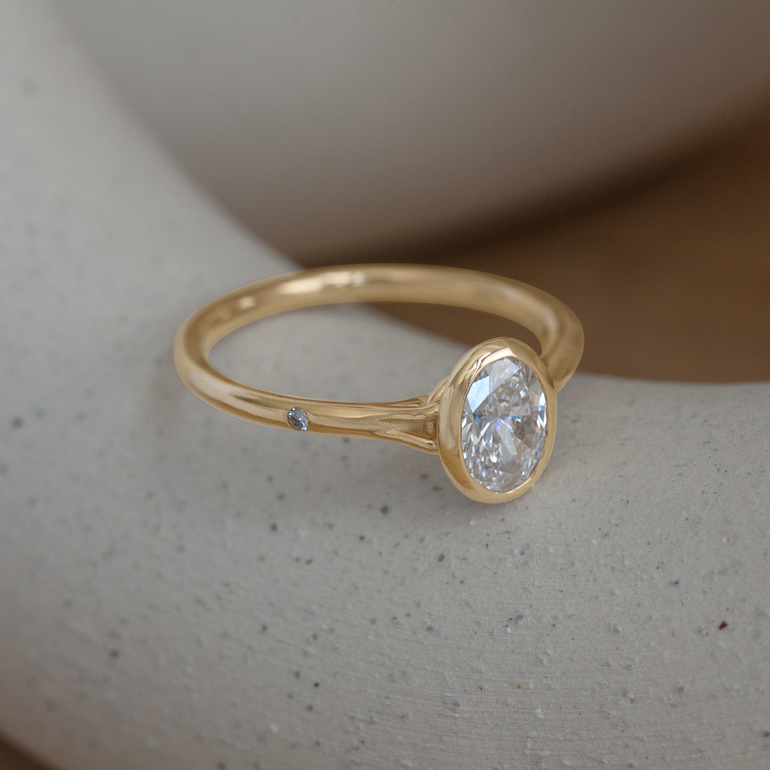 Lifestyle angled side view of Suspended in Time Ring / Oval Lab Diamond 0.79ct by Sandy Rubin on a ceramic with a blurred neutral background