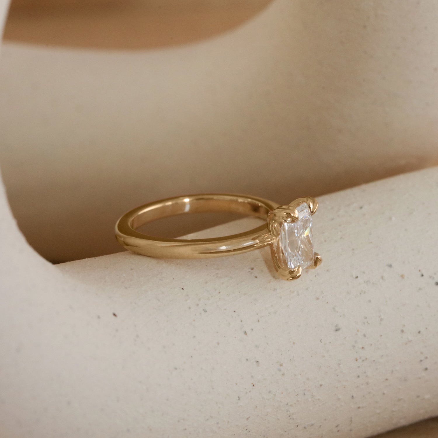 Lifestyle angled side view of Calyer Ring Radiant Lab Diamond 1ct by Goldpoint Jewelry on a ceramic with neutral background