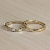 Lifestyle stacked view of Flat Band Soft Curve in Platinum and Flat Band Soft Curve in 14k yellow gold