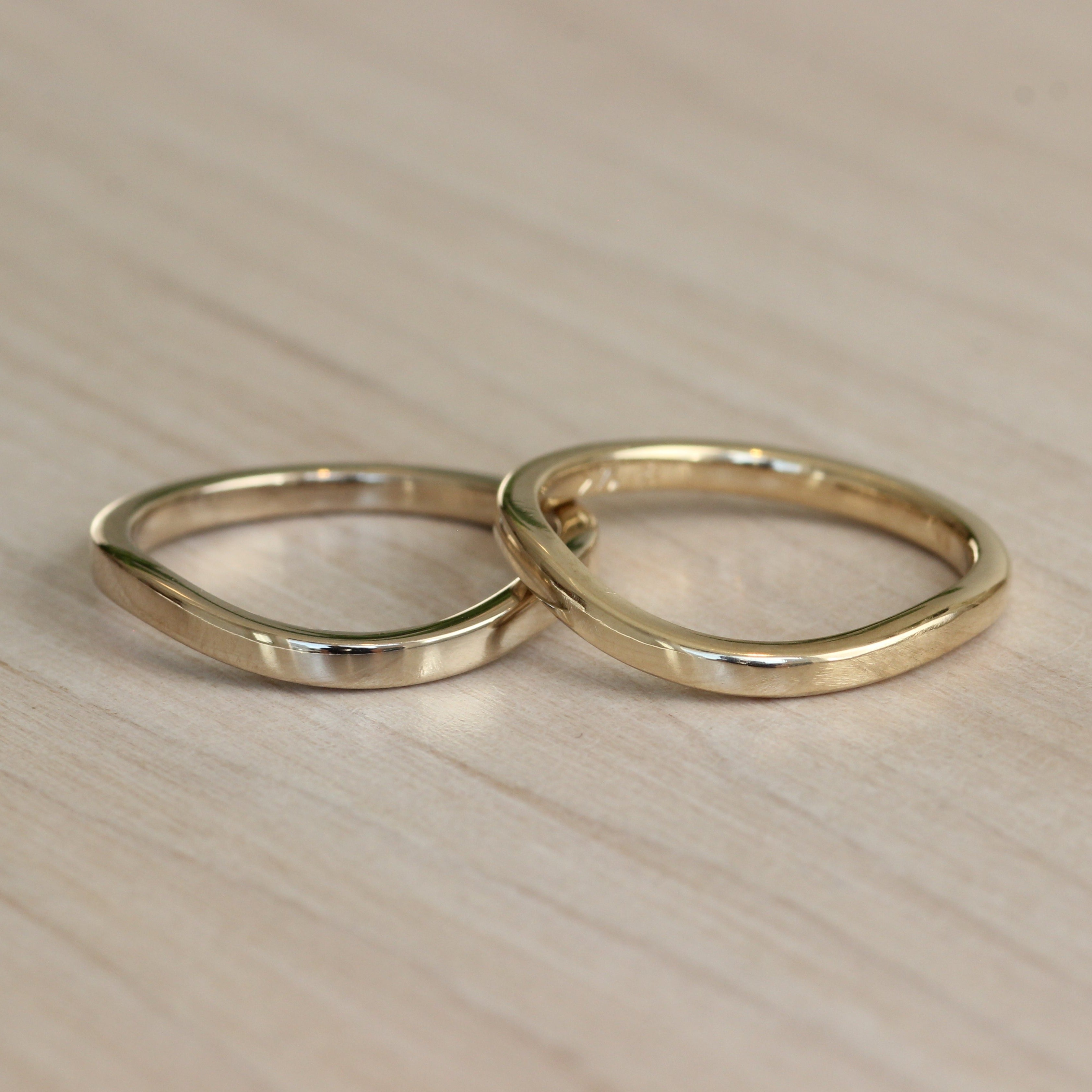 Lifestyle stacked view of Flat Band Soft Curve in Platinum and Flat Band Soft Curve in 14k yellow gold