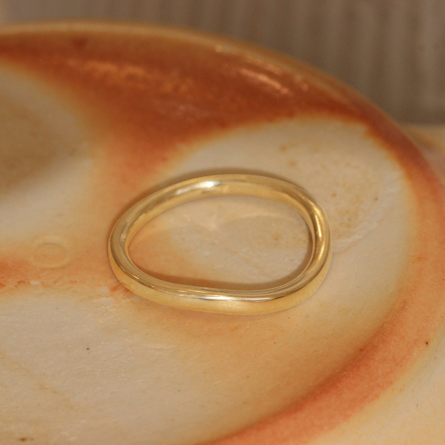 Lifestyle angled view of Flat Band Soft Curve in 14k yellow gold