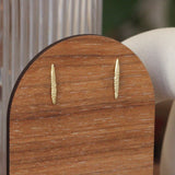 Lifestyle angled view of Spine Studs by Erin Cuff on a wooden display with wooden background