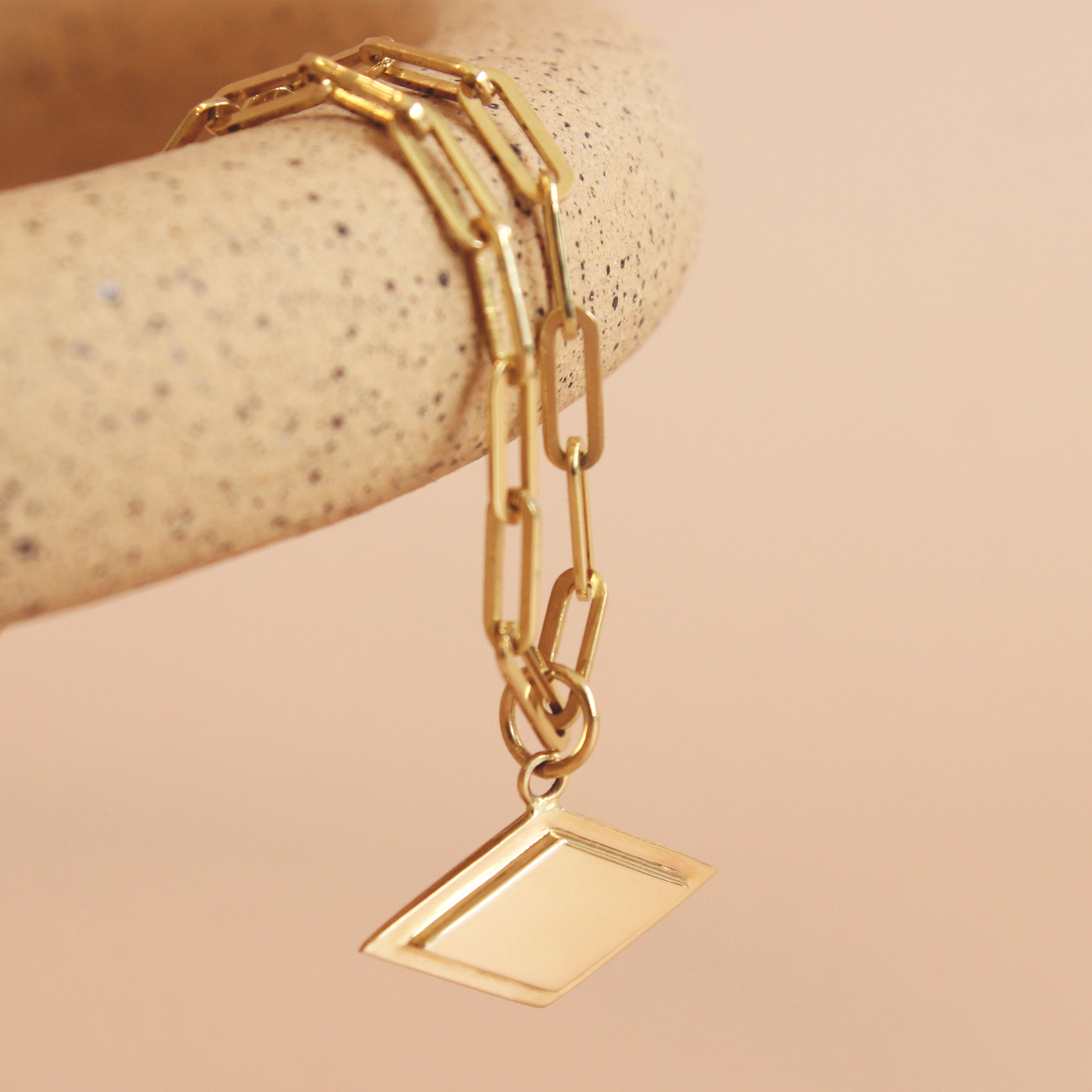 Lifestyle close angled view of Step Frame Charm / Diamond by Goldpoint Jewelry on a chain hanging on a ceramic display