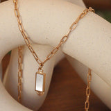 Lifestyle view of Step Inlay Rectangle Mother of Pearl Necklace / Paperclip Chain by Goldpoint Jewelry hanging over a ceramic