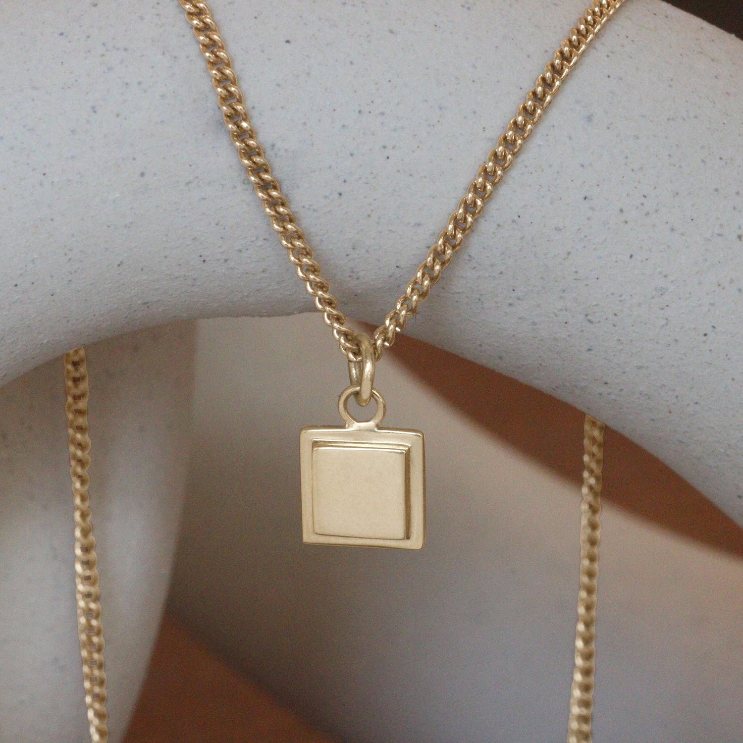 Lifestyle front view of Step Frame Square Necklace / Curb Chain on a ceramic with blurred background