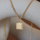 Lifestyle front view of Step Frame Square Necklace / Curb Chain on a ceramic with blurred background