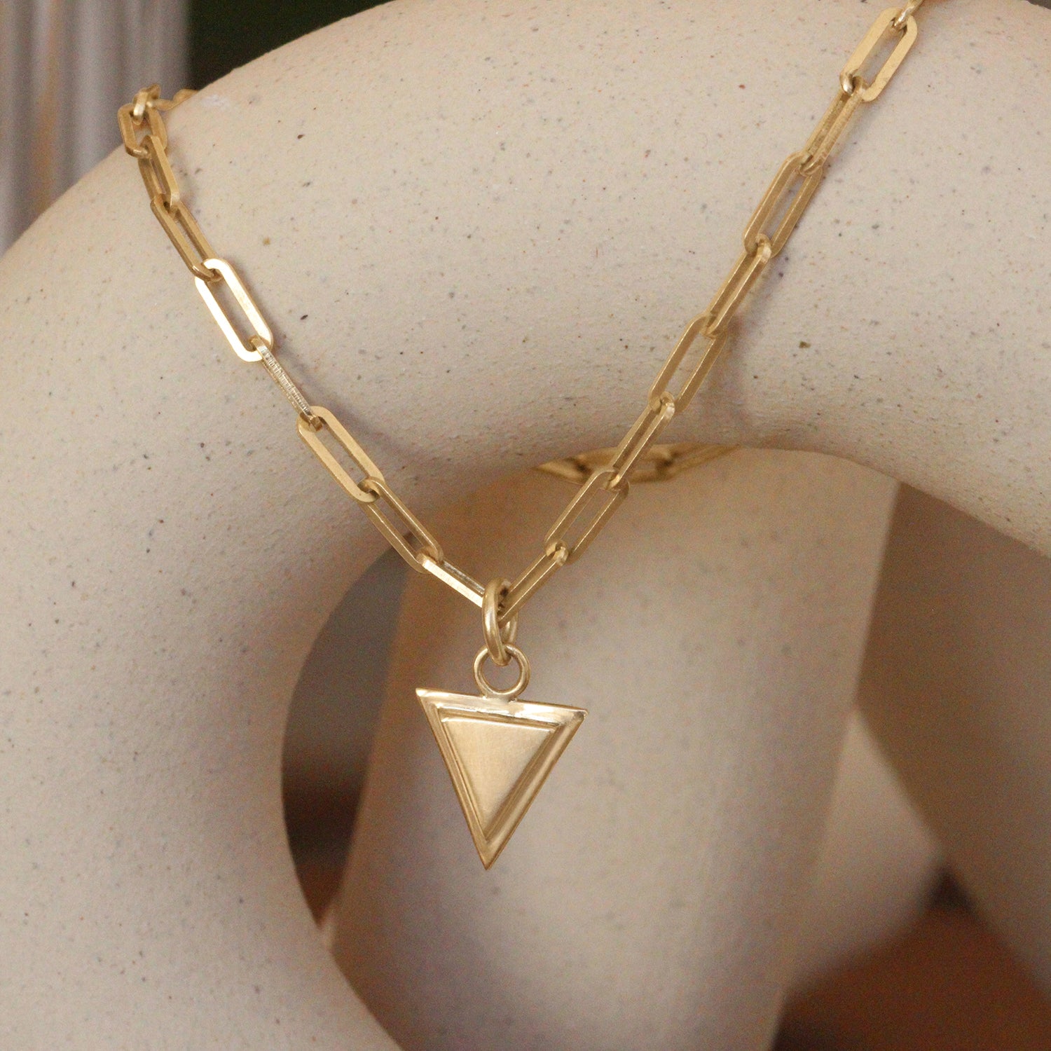 Lifestyle angled view of Step Frame Triangle Bracelet / Paperclip Chain by Goldpoint Jewelry on a ceramic