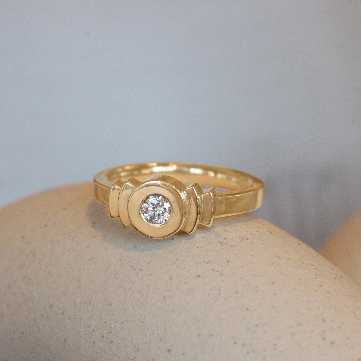 Lifestyle angled view of Step Signet Ring / Round Diamond by Goldpoint Jewelry on a ceramic with a blurred background