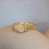 Lifestyle angled view of Step Signet Ring / Round Diamond by Goldpoint Jewelry on a ceramic with a blurred background