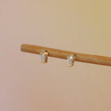 Lifestyle angled view of Split Bezel Earring / Lab Oval Diamond by Goldpoint Jewelry on a wooden stand with a gradient background