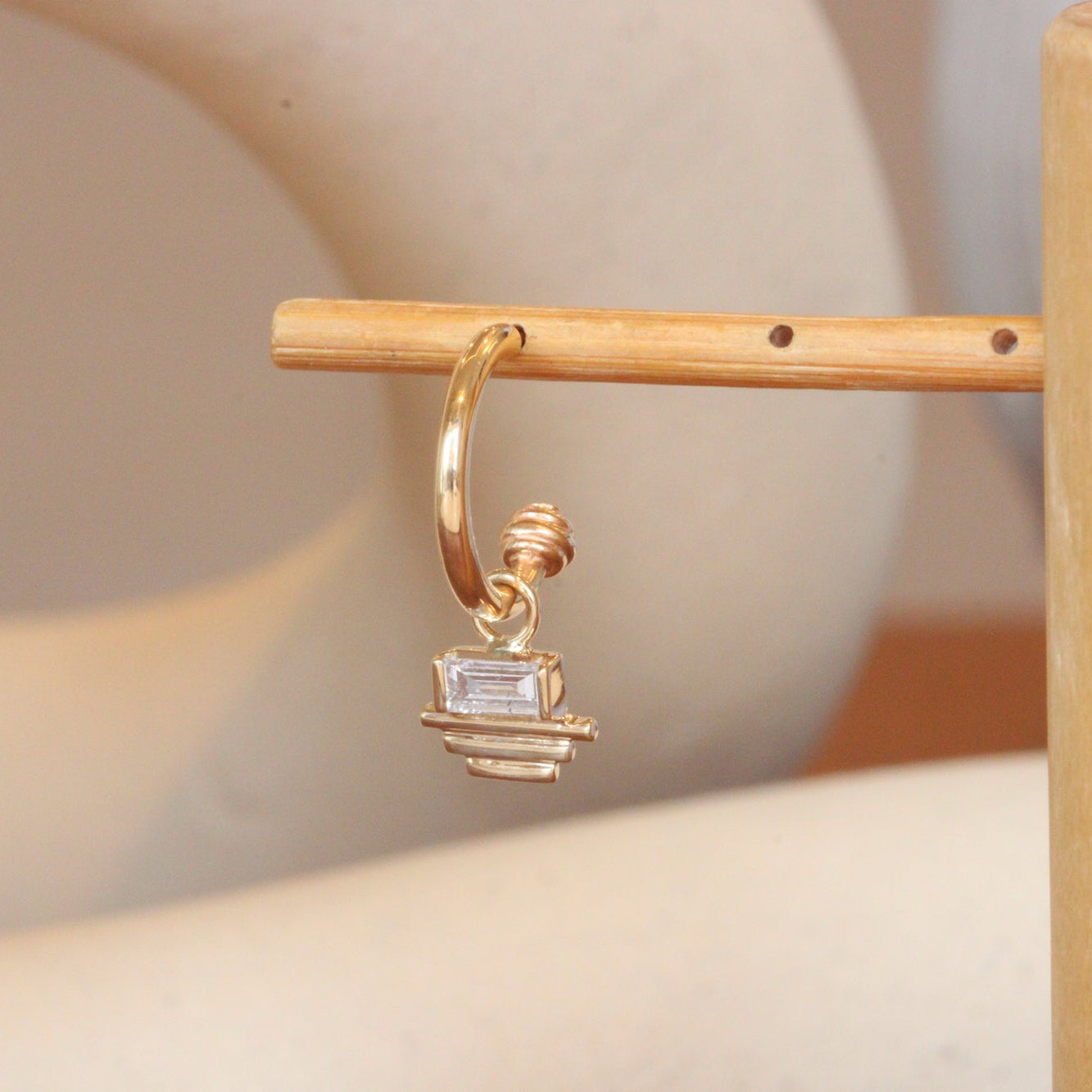 Lifestyle angled view of Front view of Step Pyramid Charm / Lab Baguette Diamond on a Cornice Hoop by Goldpoint Jewelry  on a wooden earring stand