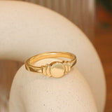 Lifestyle angledside view of Step Signet Ring / Circle by Goldpoint Jewelry on a ceramic with blurred background