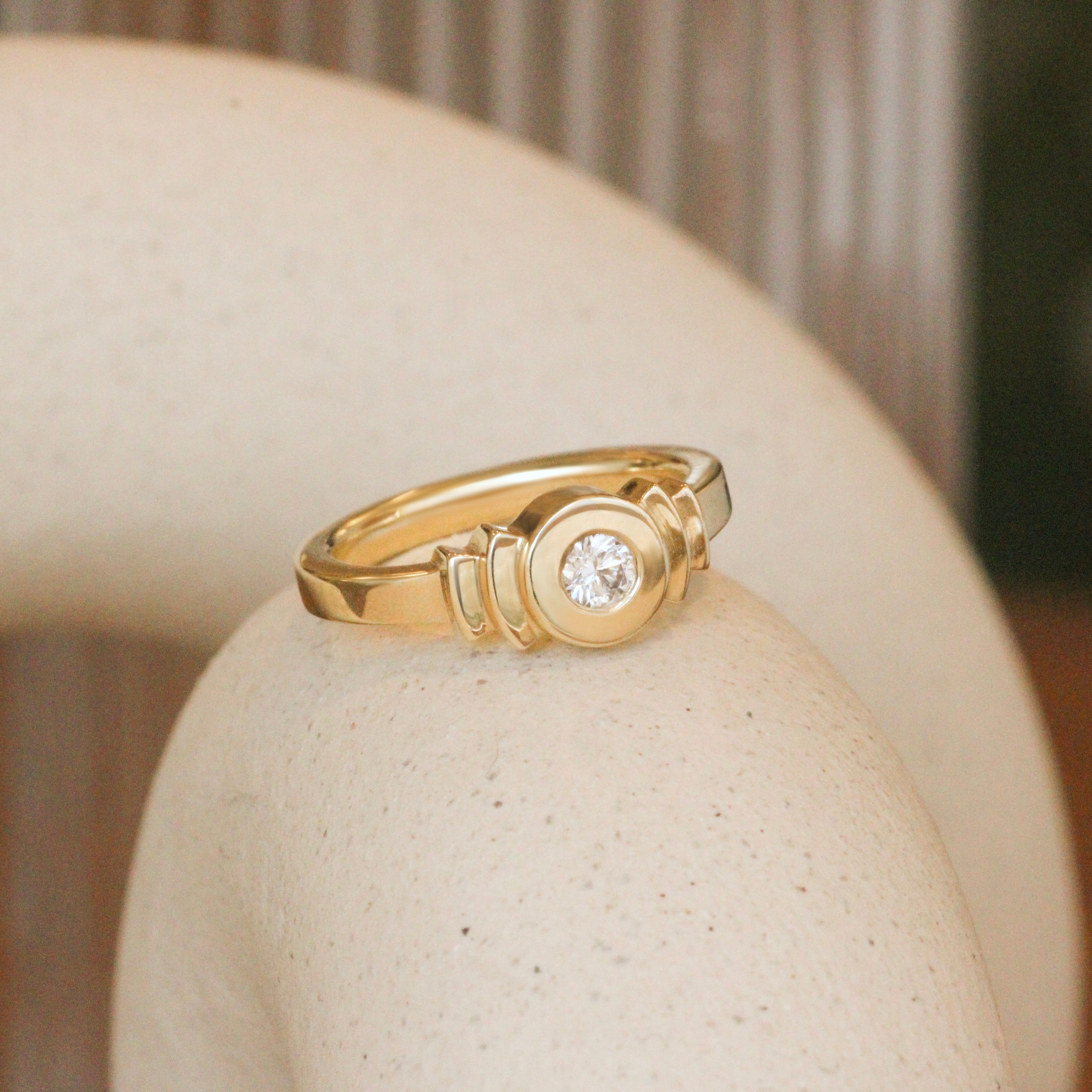 Lifestyle angled view of Step Signet Ring / Round Diamond by Goldpoint Jewelry on a ceramic with a blurred background