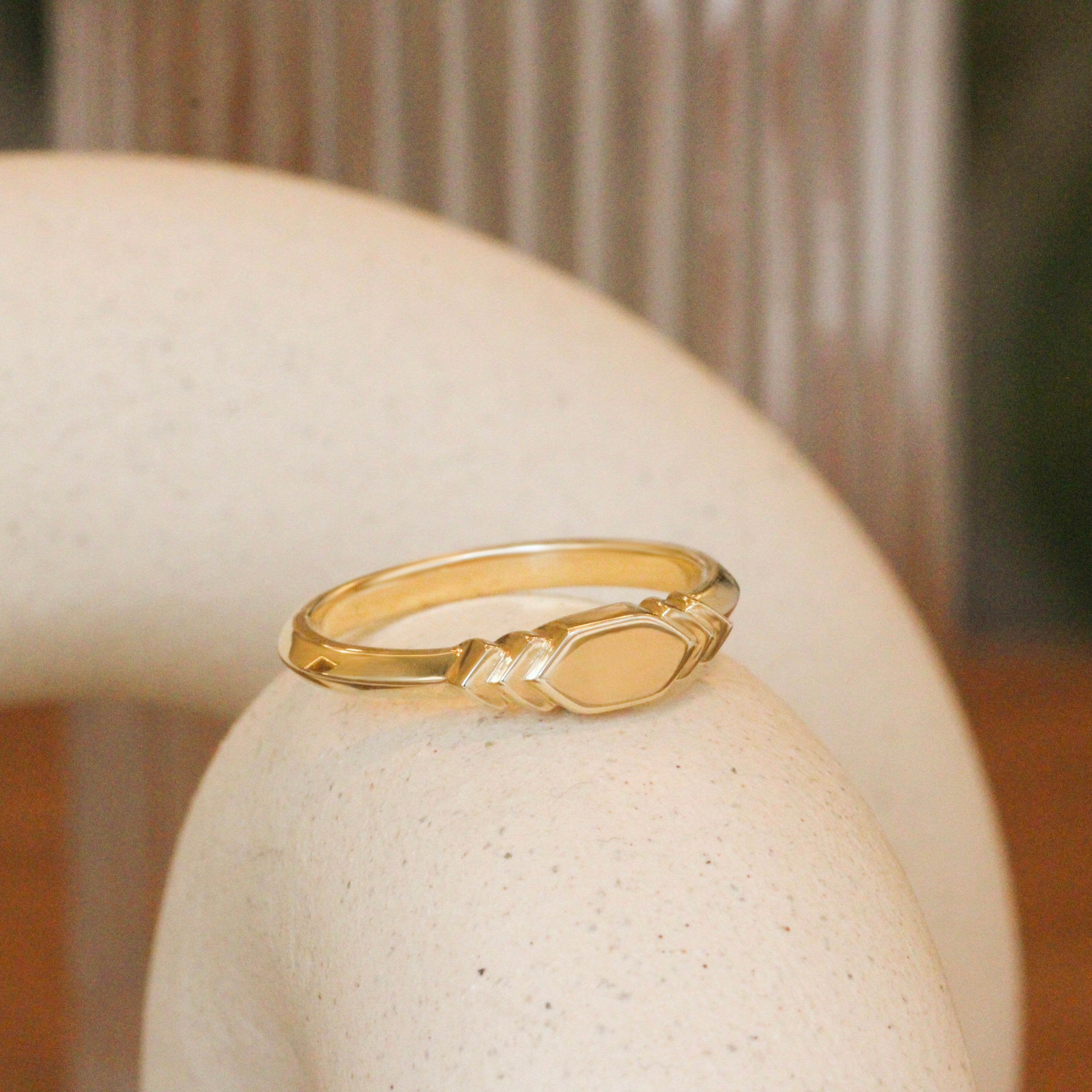 Lifestyle angled view of Step Signet Ring / Hexagon by Goldpoint Jewelry on a ceramic with a blurred background