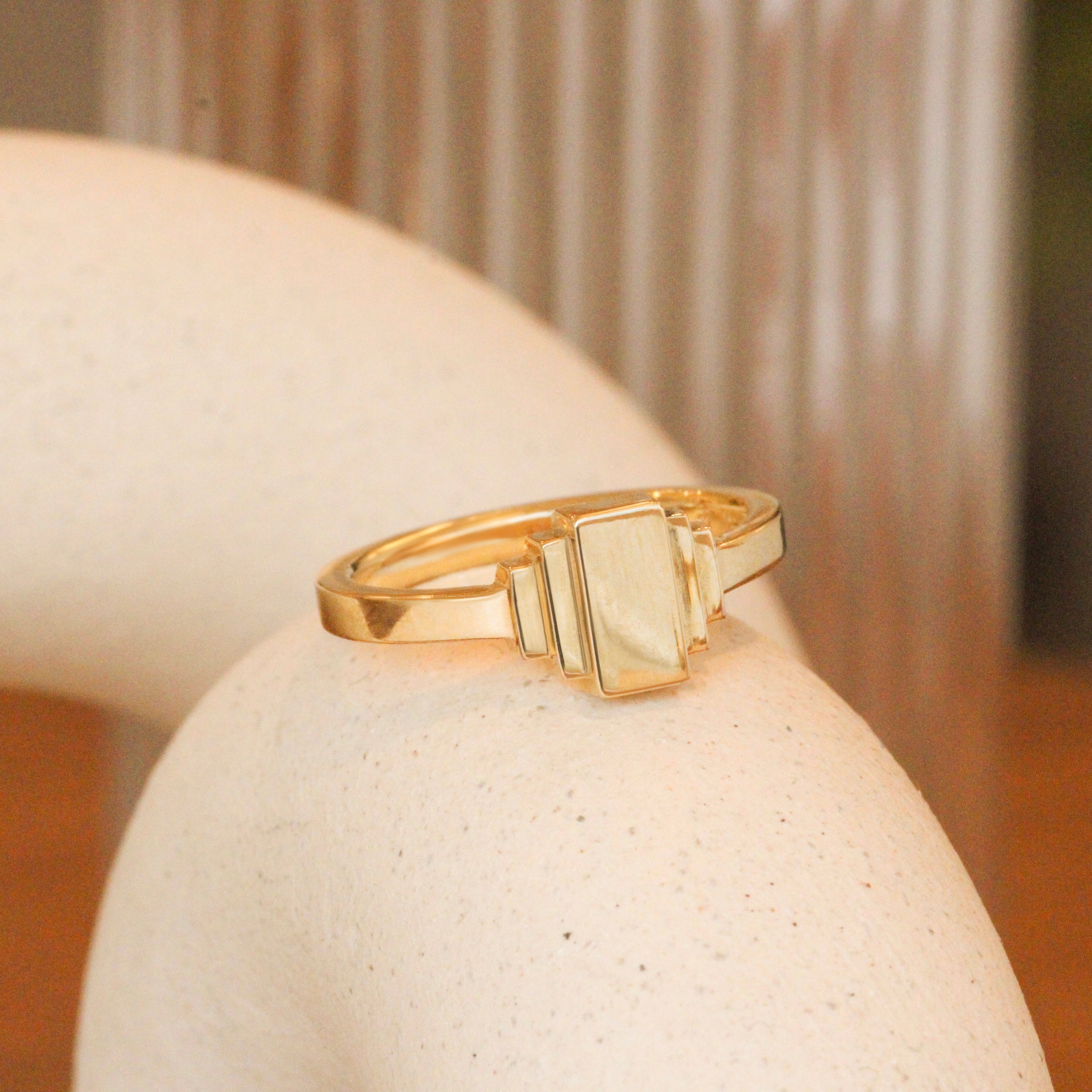 Lifestyle angled view of Step Signet Ring / Rectangle by Goldpoint Jewelry on a ceramic with a blurred background
