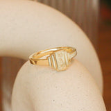 Lifestyle angled side view of Step Signet Ring / Rectangle + Engraving by Goldpoint Jewelry on a ceramic with blurred background