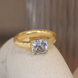 Lifestyle angled view of Sutton Ring Emerald Cut Sapphire 2.1ct by Goldpoint Jewelry on a ceramic with blurred background