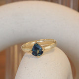 Lifestyle angled view of Sutton Ring Pear Sapphire 1.28ct by Goldpoint Jewelry on a ceramic with a blurred background