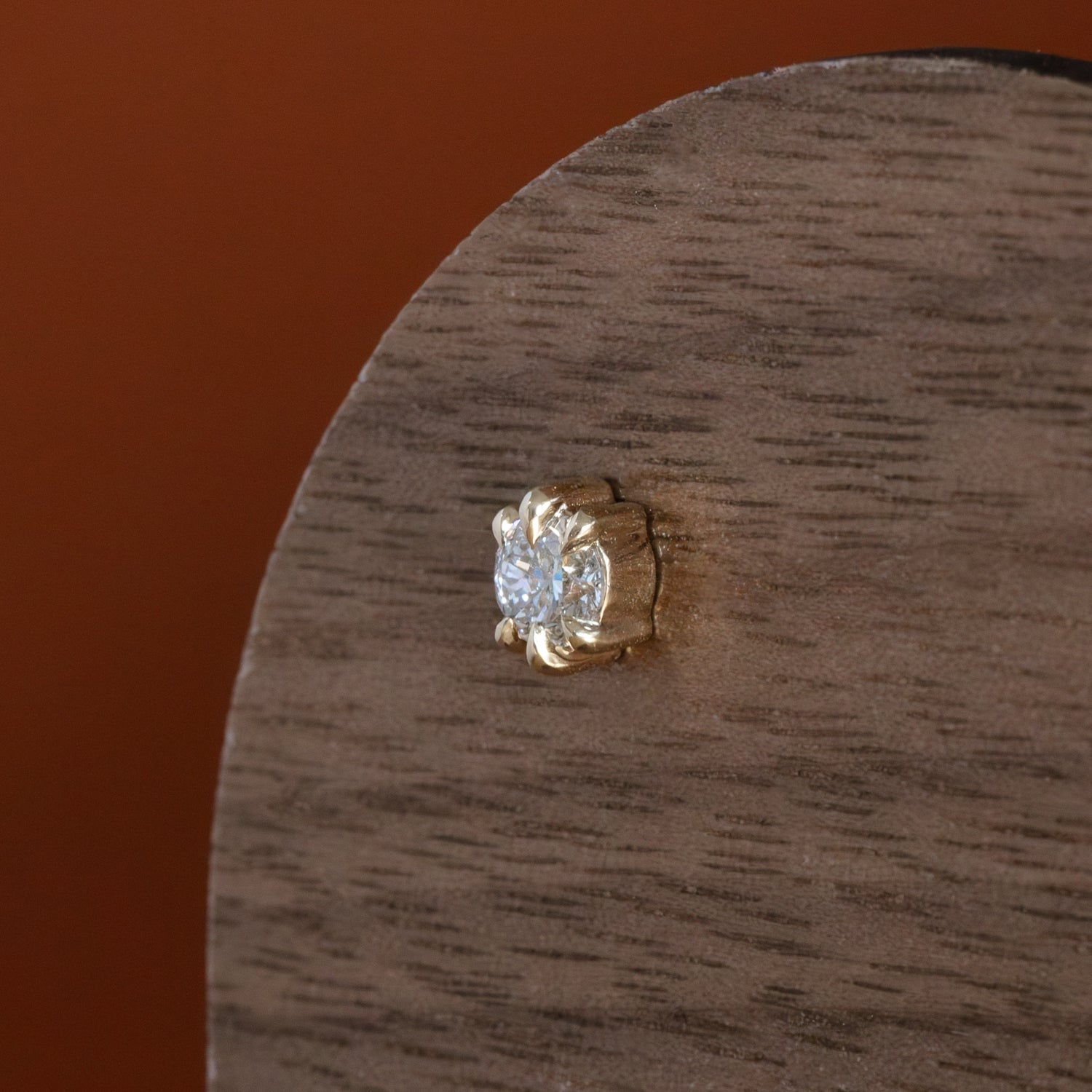Lifestyle angled view of Talon Earring Medium / Lab Grown Diamond by Goldpoint Jewelry on a wood display with an orange background