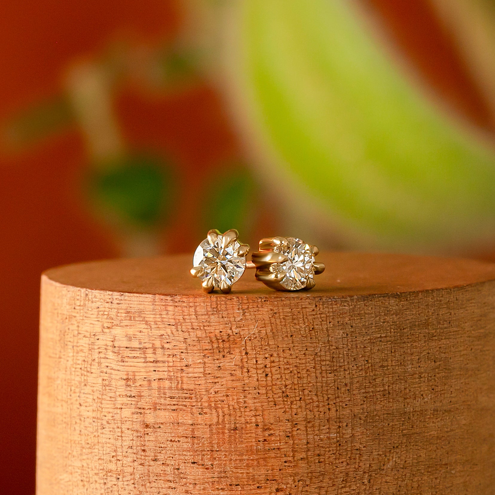 Front view of two pieces of Talon Earring Single / 5mm Old Lab Grown Diamond by Goldpoint Jewelry on a wooden display with blurred backdrop