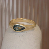 Lifestyle angled view of Teal Sapphire Signet Ring / Pear Cut Sapphire 0.86ct by 12th House on a ceramic on a blurred background