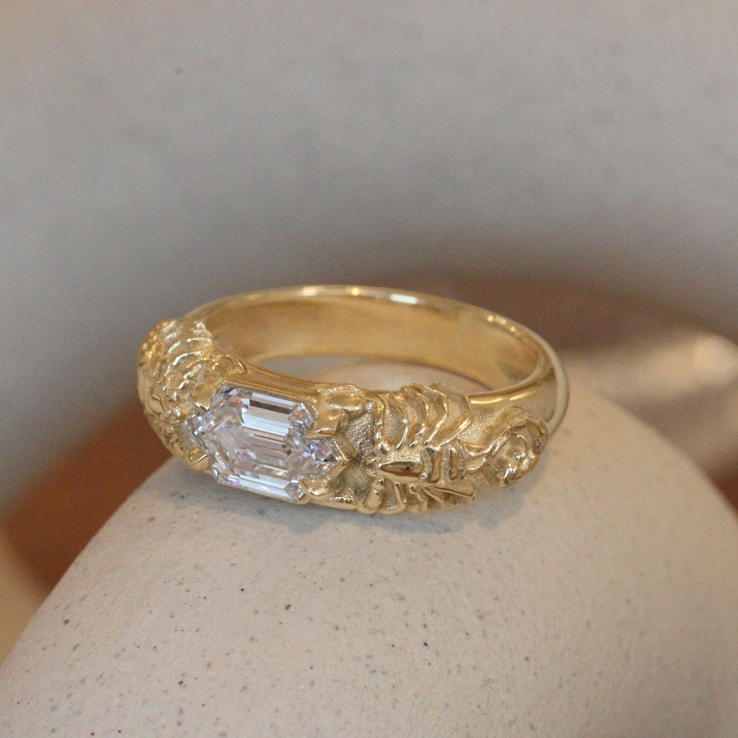 Lifestyle angled side view of Twin Scorpion Ring / Elongated Hexagon Lab Diamond 1.10ct by Amour Vee on a ceramic with a blurred background
