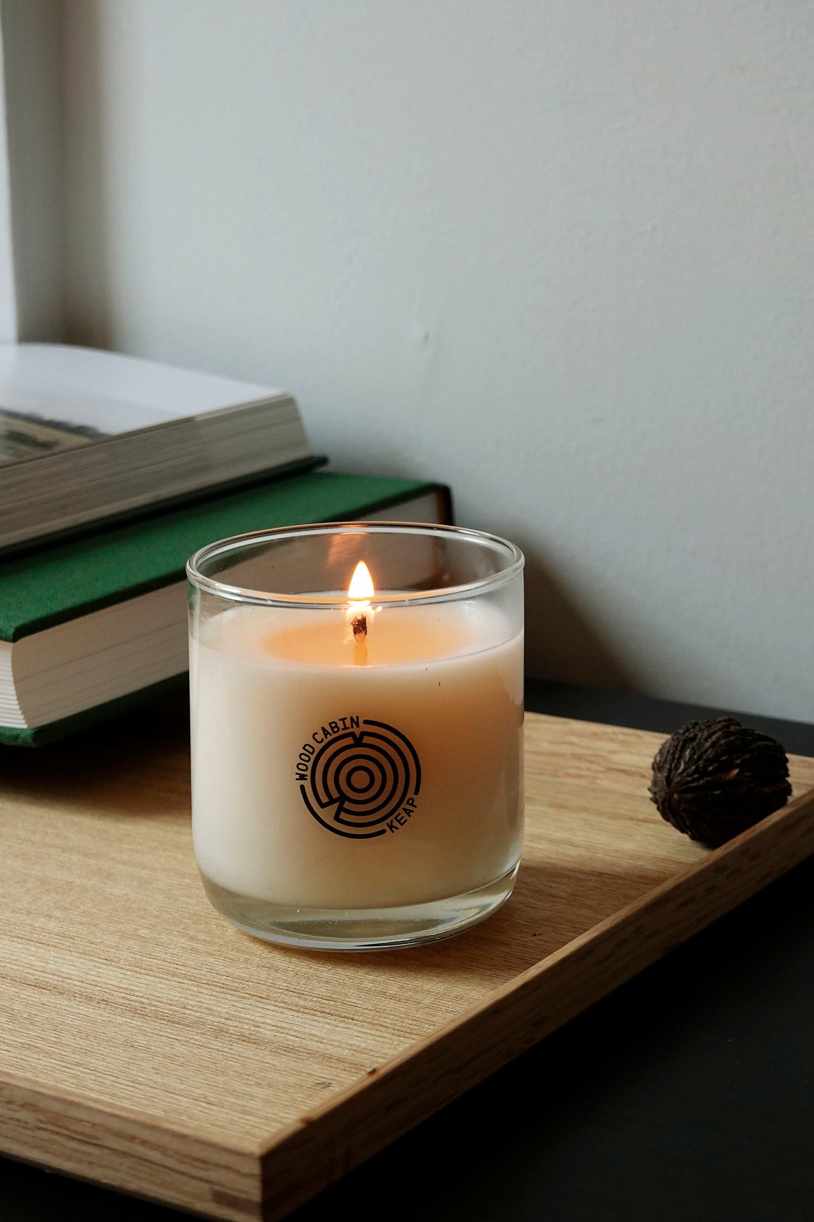 Lifestyle view of Wood Cabin Scented Candle by Keap Candles on a shelf with decorative objects