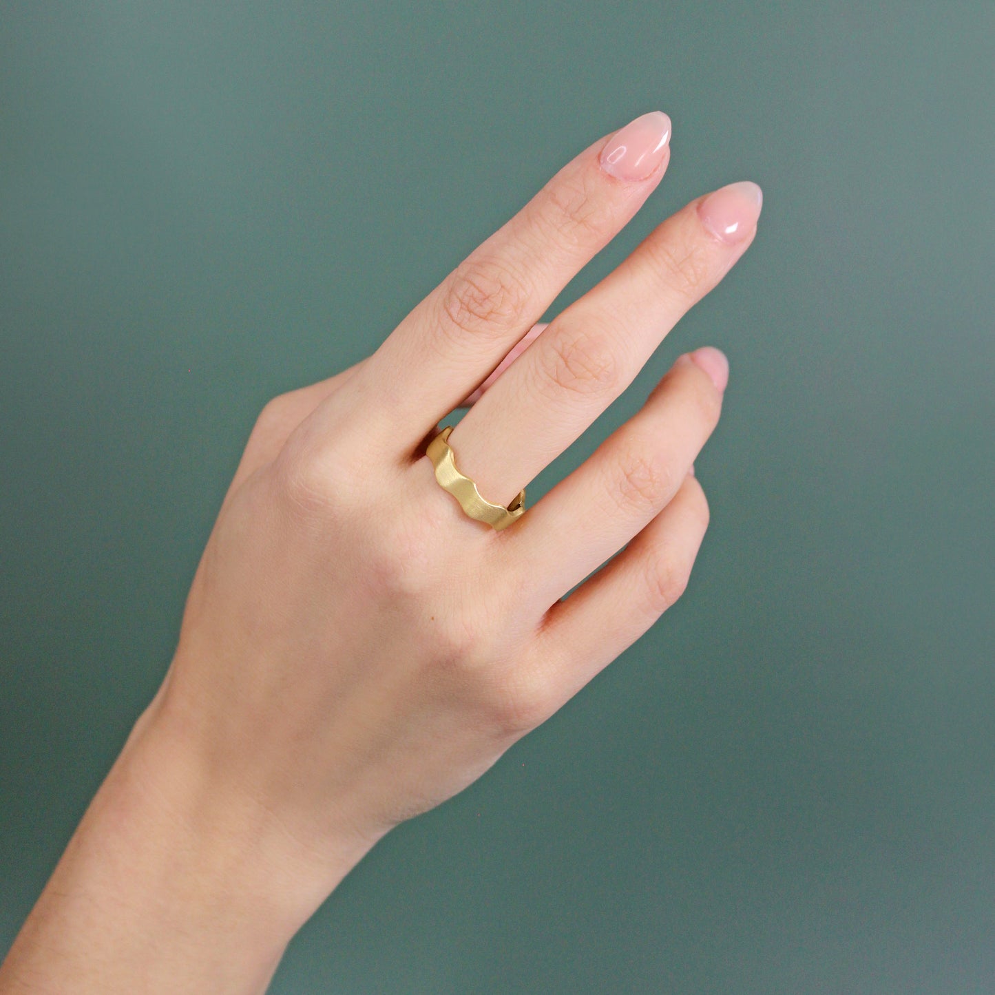 Model wears Waves Band / Wide in 18k yellow gold on middle finger by Goldpoint
