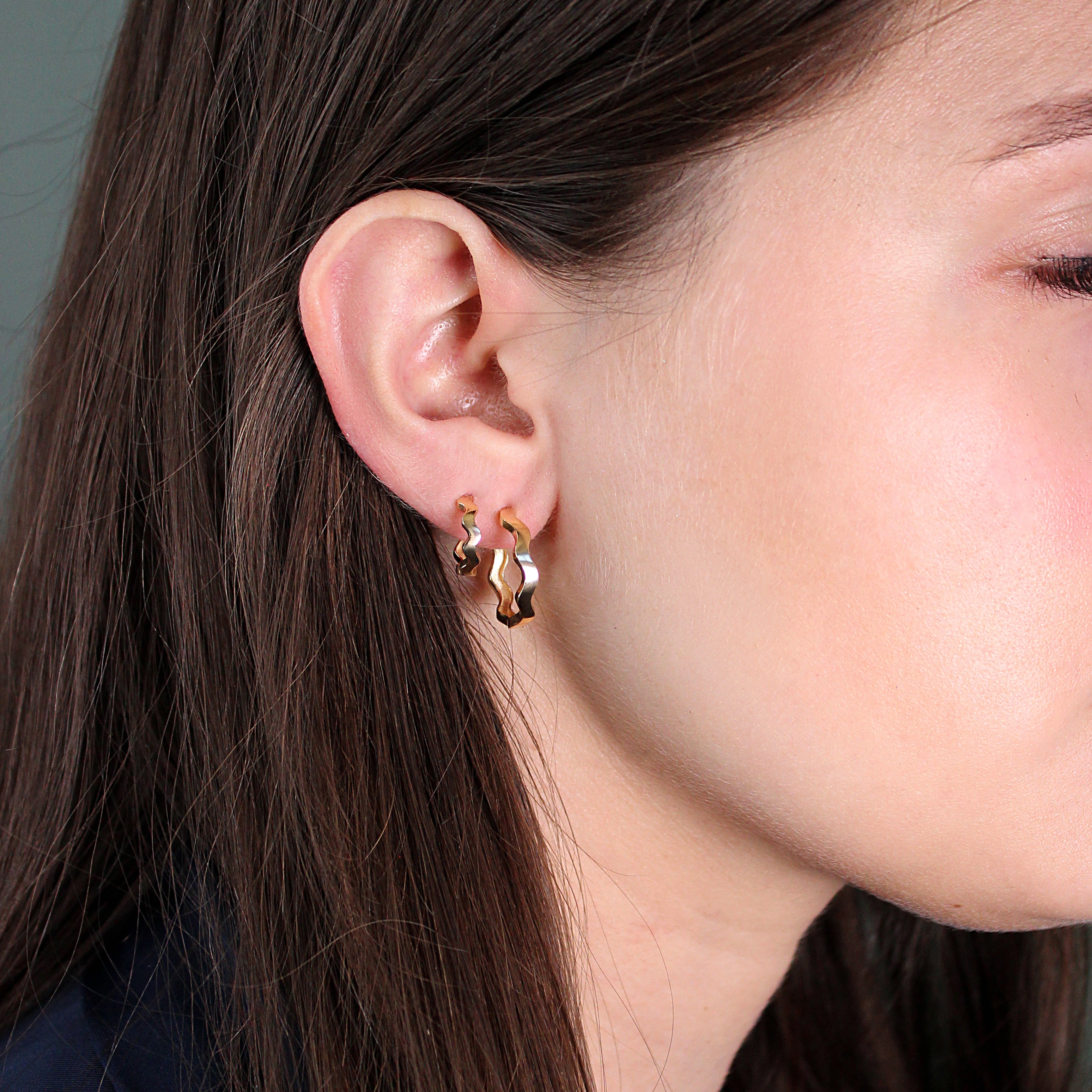 Model wears Waves Hoop / Small and Waves Hoop / Large pieces by Goldpoint Jewelry on their ear