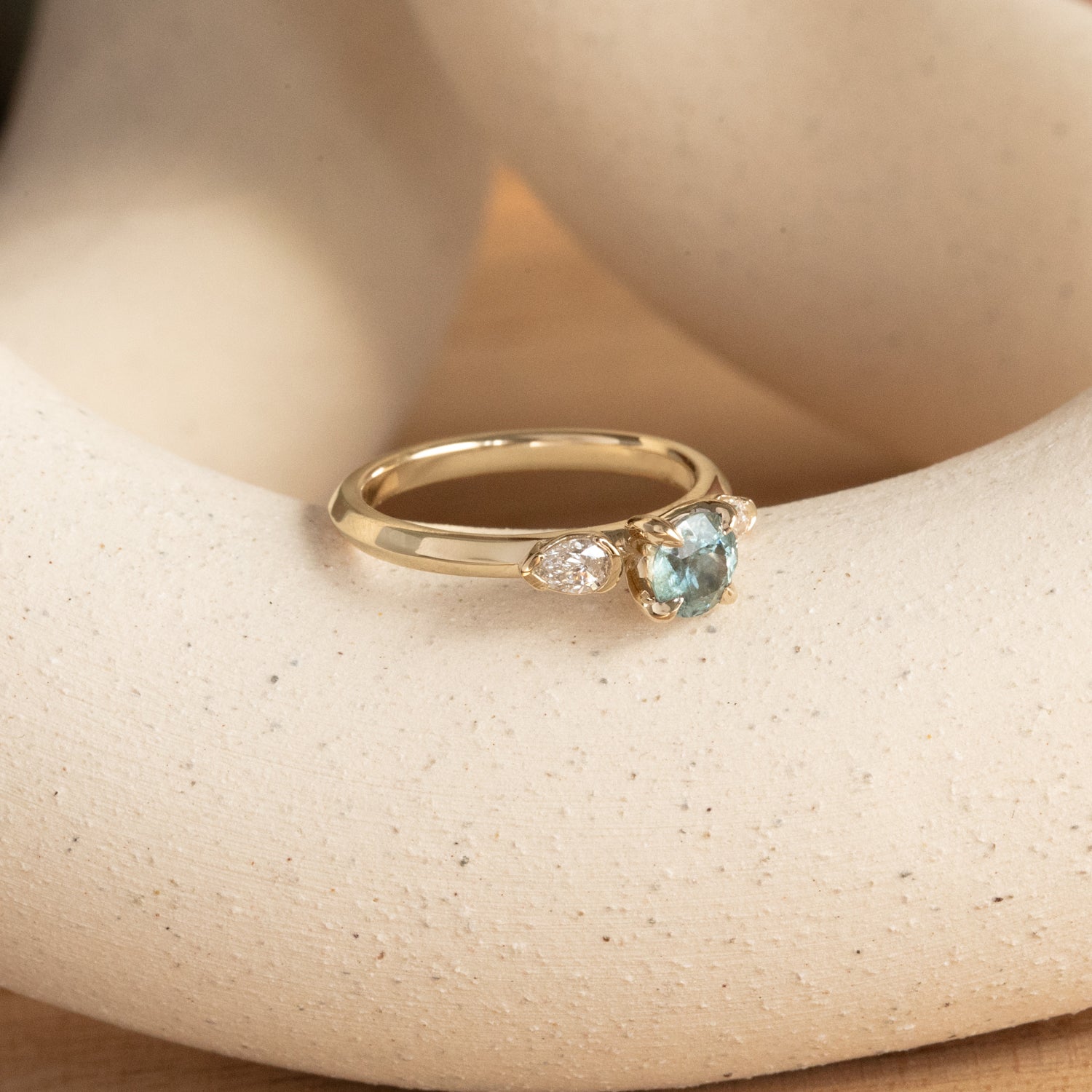 Lifestyle angled view of Wythe Ring Round Sapphire 0.69ct by Goldpoint Jewelry on a ceramic with taupe background