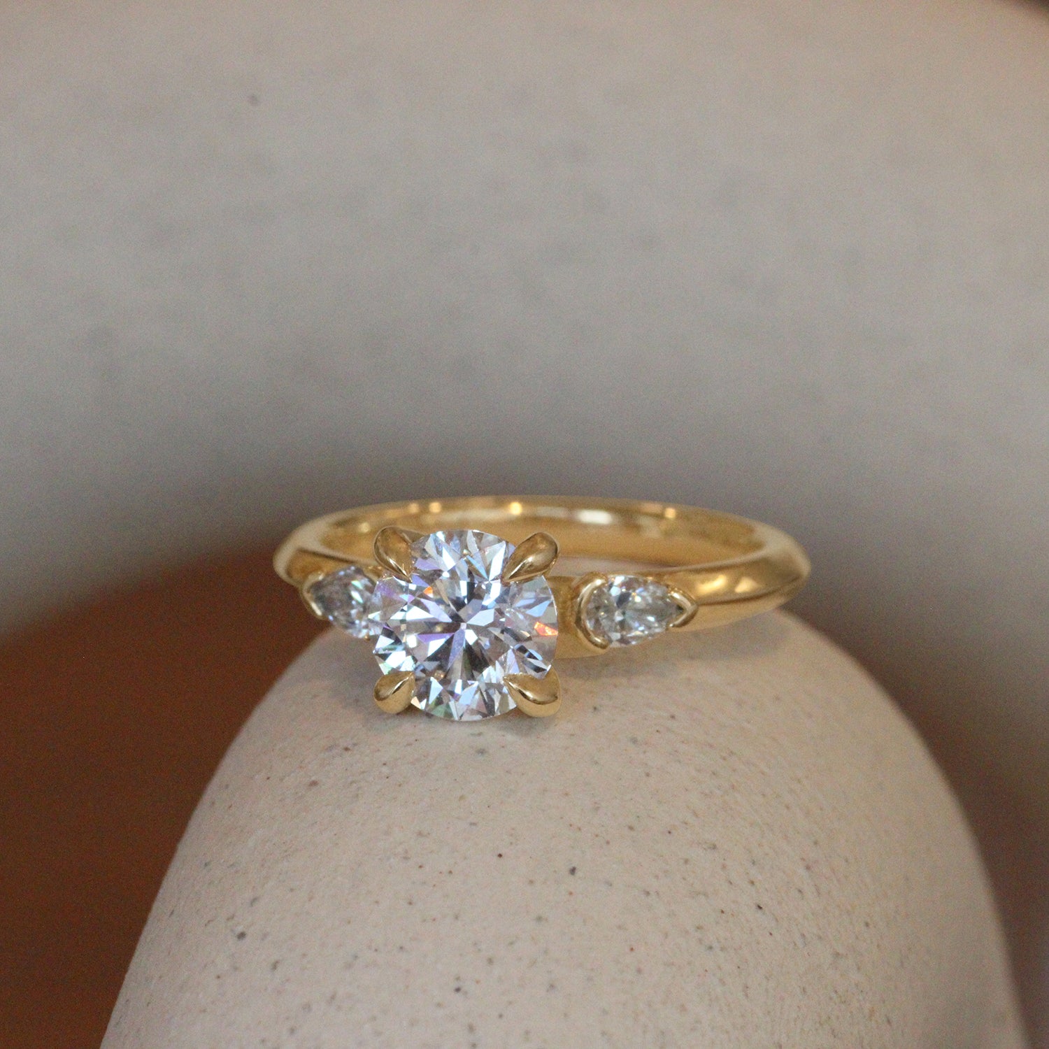 Lifestyle angled view of Wythe Ring Round Diamond 1.23ct by Goldpoint Jewelry on a ceramic with a blurred background