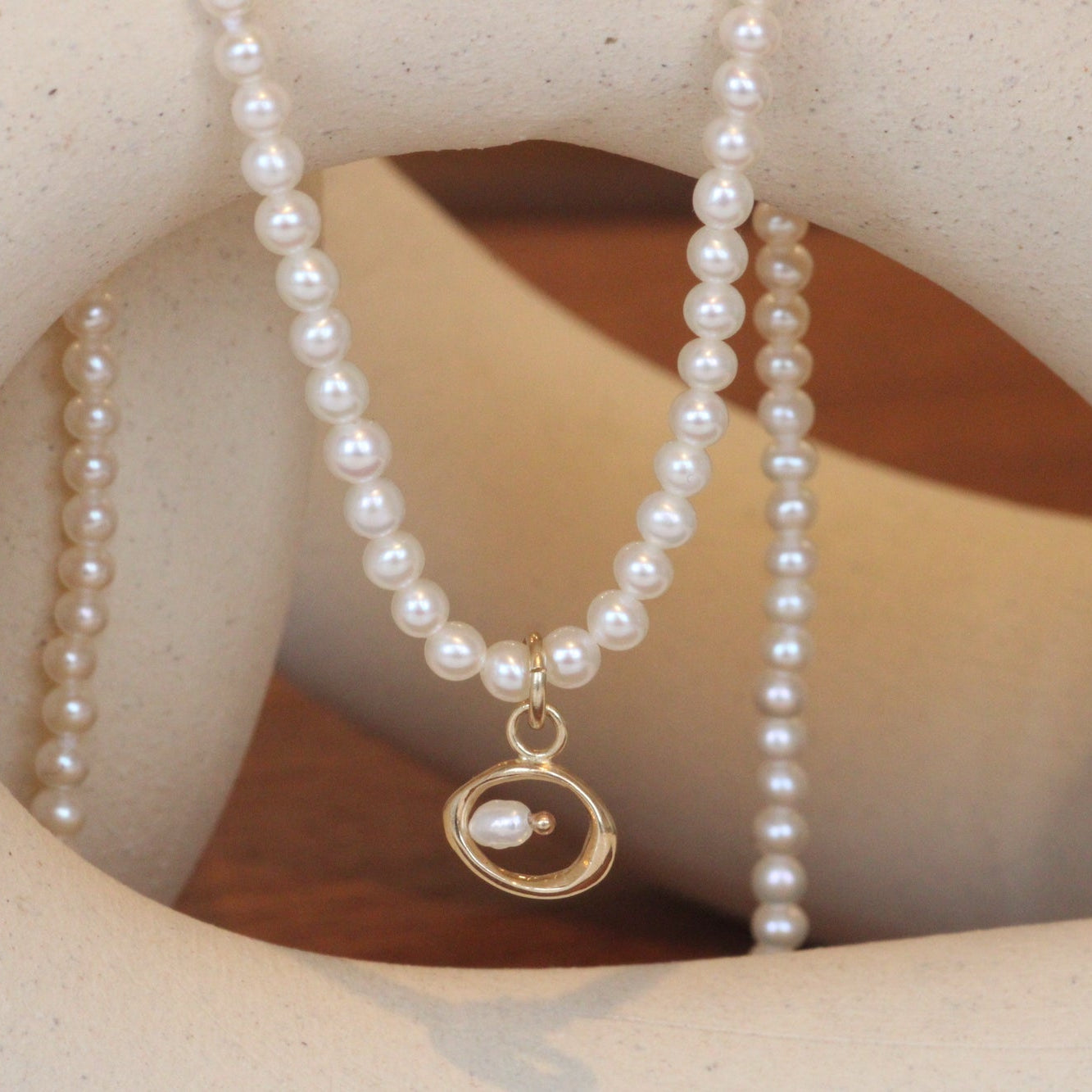 Front view of Amorphous Pearl Bead Charm / Small Circle by Goldpoint Jewelry on a pearl necklace