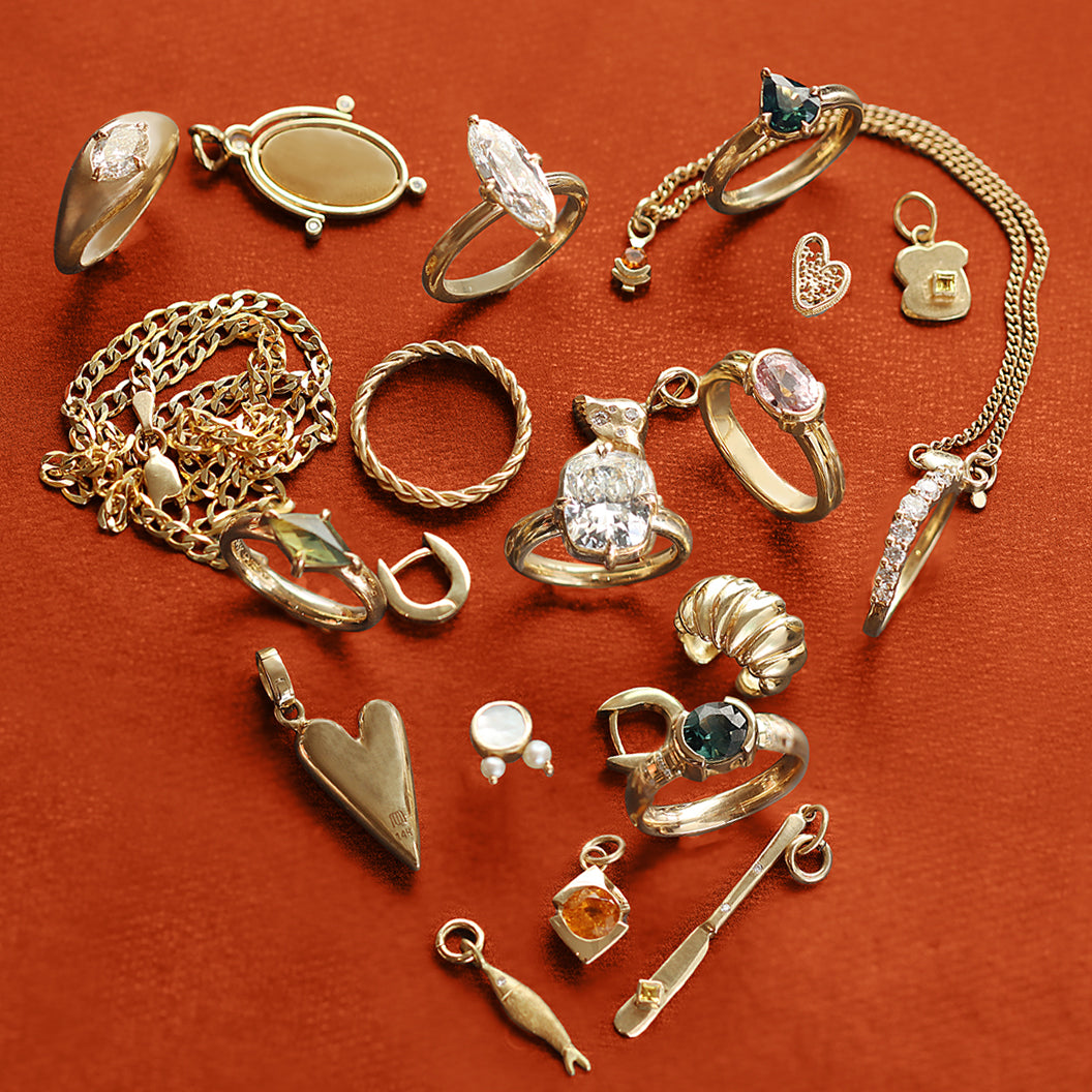 Various Goldpoint Jewelry fine jewelry pieces forming a heart shape on an orange backdrop