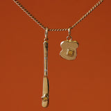 Pendant featuring Fancy Butter Knife Charm / Princess Cut Sapphire and Toast Charm / Princess Cut Sapphire in 14k yellow gold by Oxbow Designs on a orange background