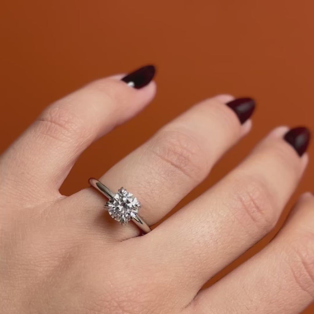Model wears Calyer Ring Round Lab Diamond 1.53ct by Goldpoint Jewelry on ring finger while showing different angles over an orange backdrop