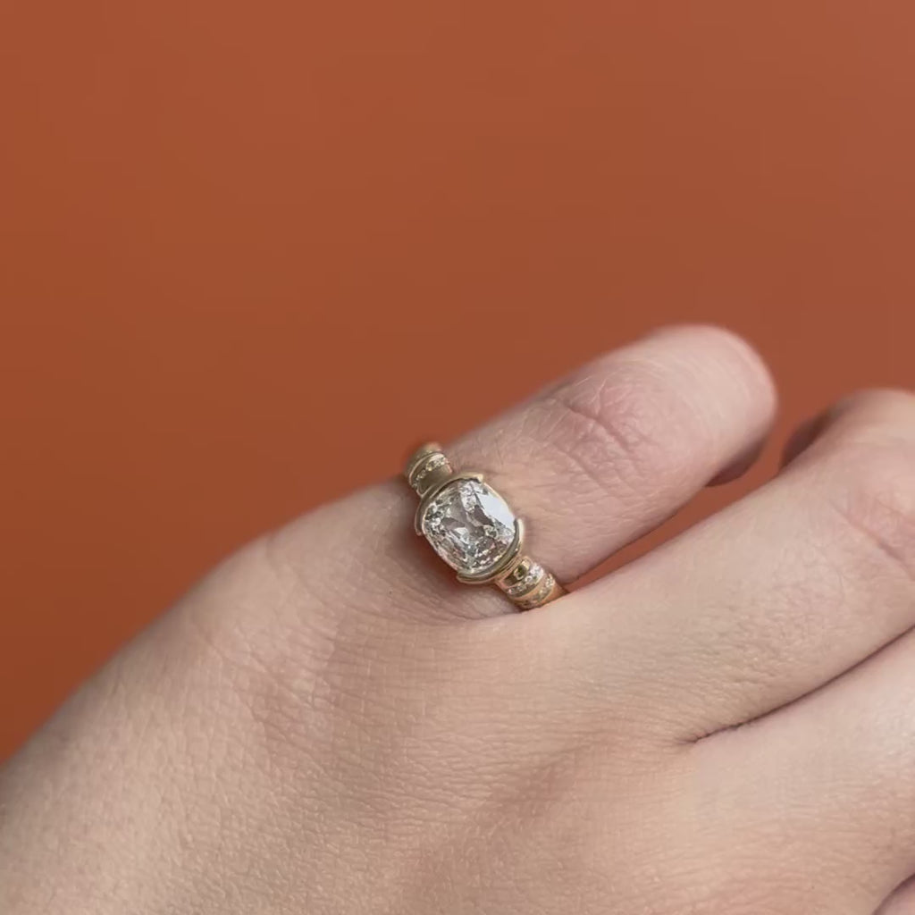 Model wears Dobbin Ring Antique Oval Cushion Diamond 1.28ct by Goldpoint Jewelry on pinky ring while showing different angles over an orange backdrop