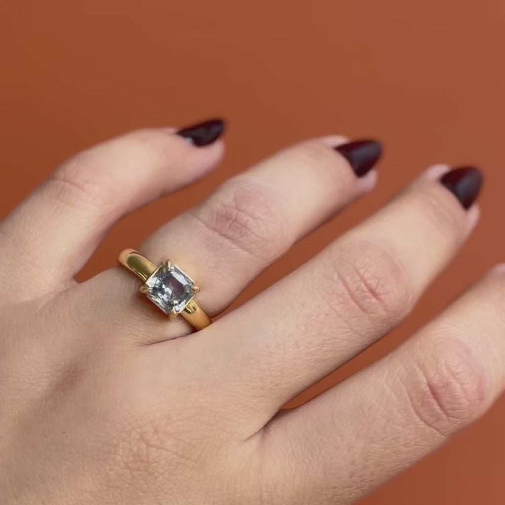 Model wears Sutton Ring Emerald Cut Sapphire 2.1ct by Goldpoint jewelry on ring finger showing different angles over an orange backdrop