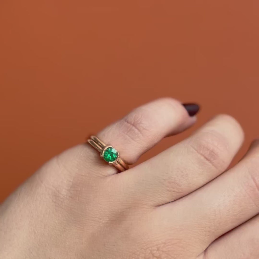 Model wears the Franklin Ring Round Emerald 0.5ct by Goldpoint Jewelry on the pinky while showing different views over an orange backdrop