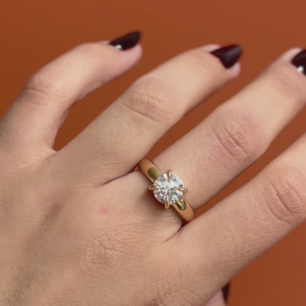 Model wears Sutton Ring Round Lab Diamond 2.12ct by Goldpoint Jewelry on middle finger showing different angles over an orange backdrop