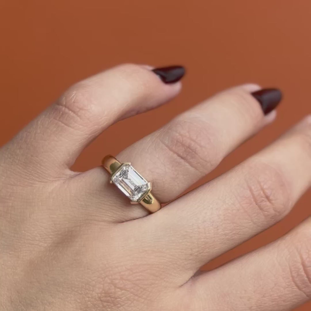 Model wears Dobbin Ring Emerald Cut Lab Diamond 2.02ct by Goldpoint Jewelry on ring finger while showing different angles on an orange backdrop