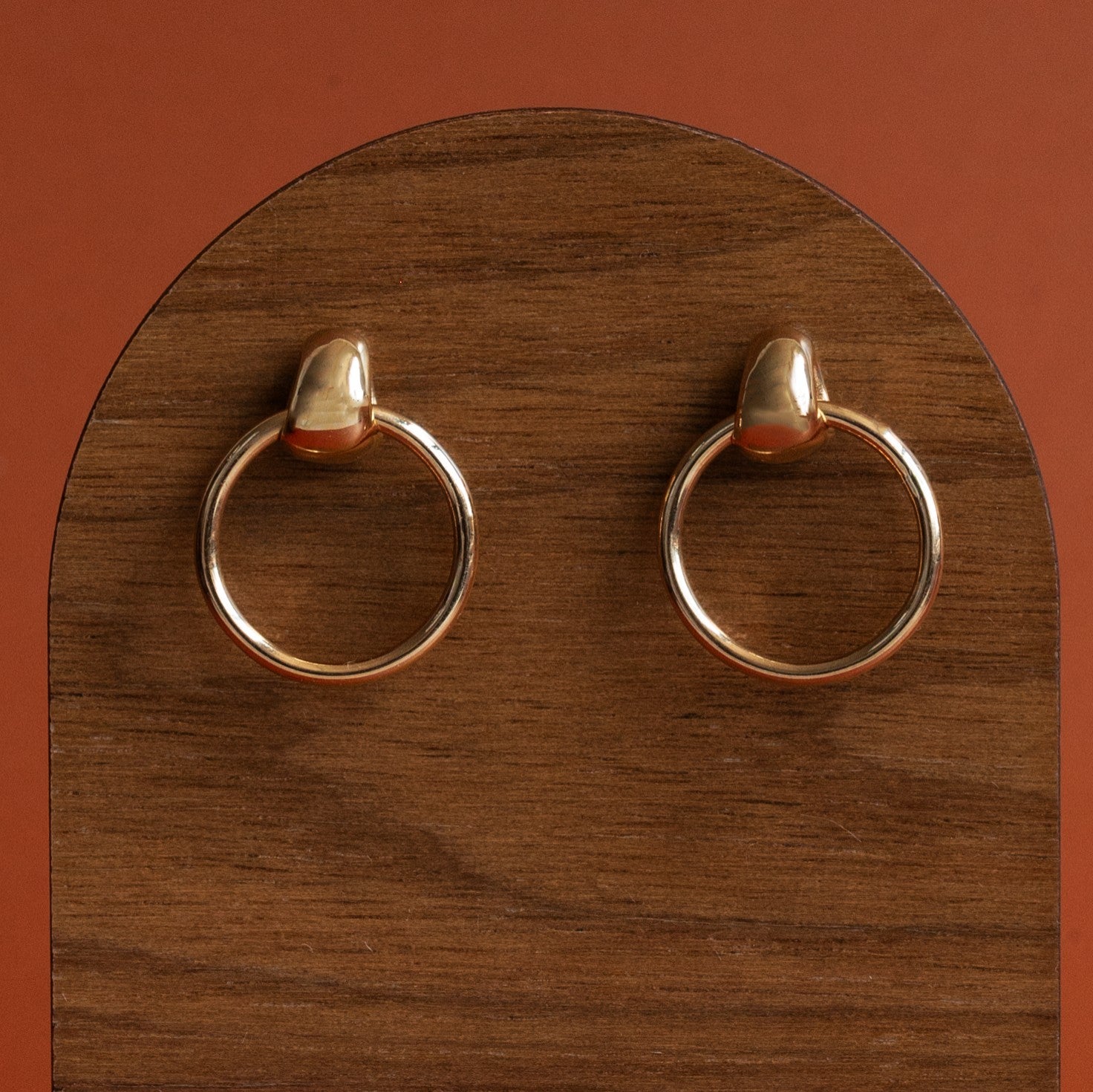 A set of yellow gold stud earrings by Goldpoint on a wooden display with orange backdrop