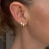 Model wears a set of Solid Huggie Hoops by Mon Pilar in ear
