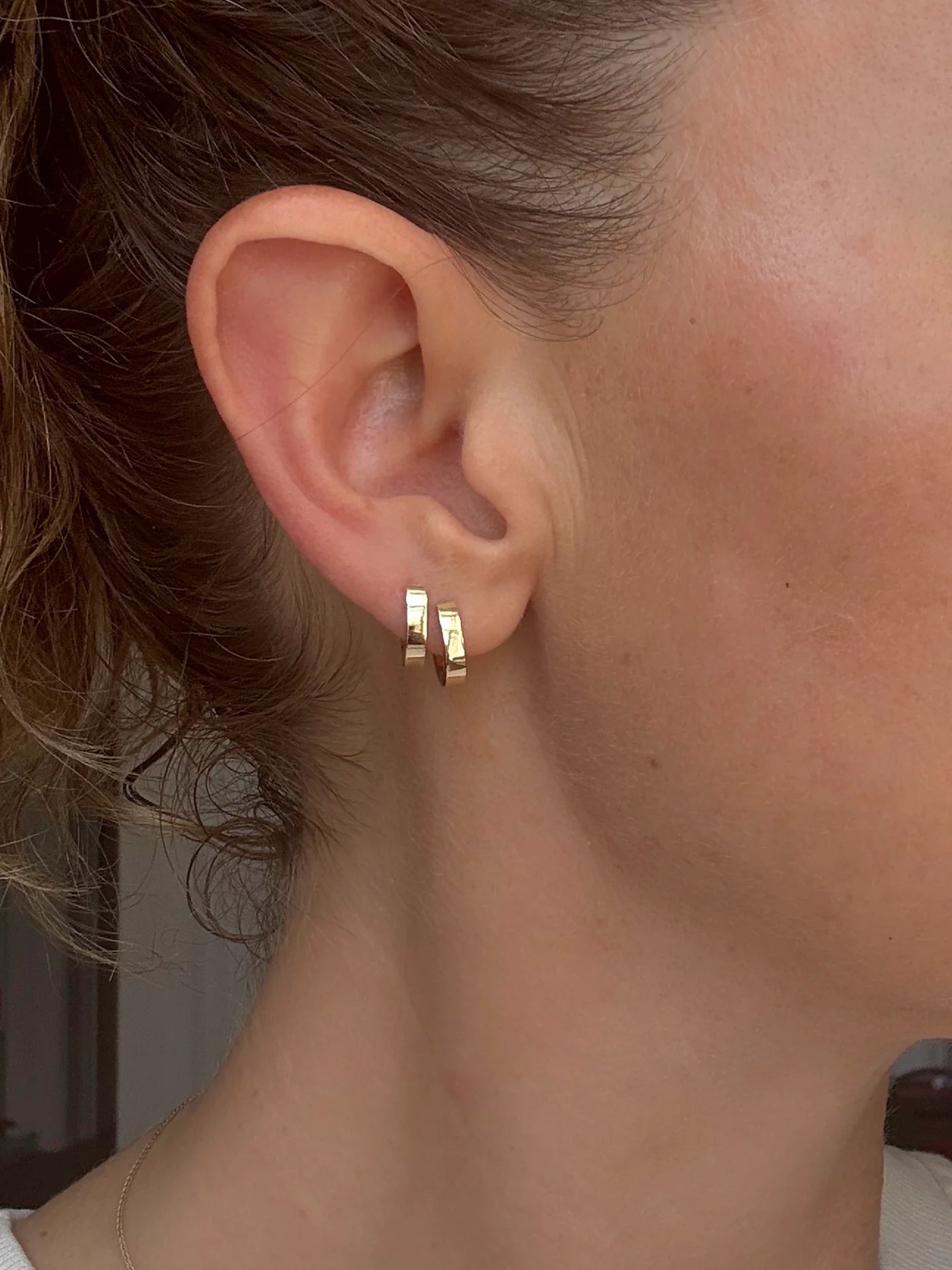 Model wears a set of Solid Huggie Hoops by Mon Pilar in ear