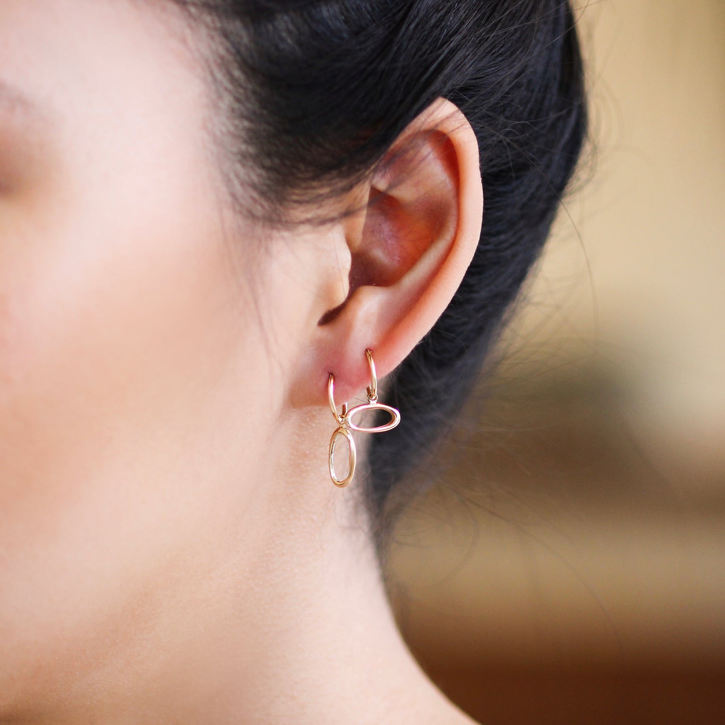 Model wears Amorphous Charm / Oval Longways by Goldpoint as a hoop earring with another earring configuration with Amorphous Charm / Oval Sideways with a hoop earring