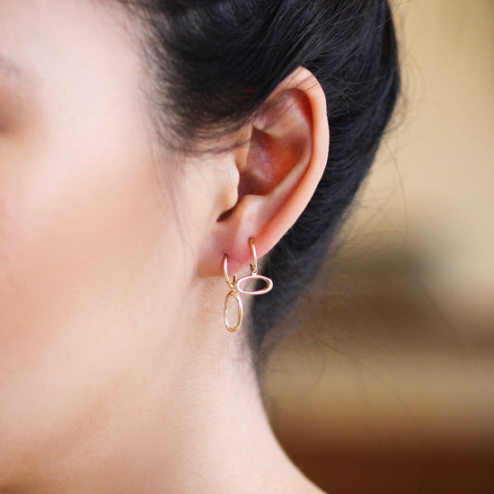 Model wears Amorphous Charm / Oval Longways by Goldpoint as a hoop earring with another earring configuration with Amorphous Charm / Oval Sideways with a hoop earring