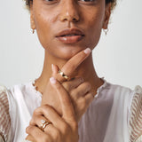 Model wears Waves Band in 14k Yellow Gold stacked with engagement ring on ring finger amongst other Goldpoint pieces