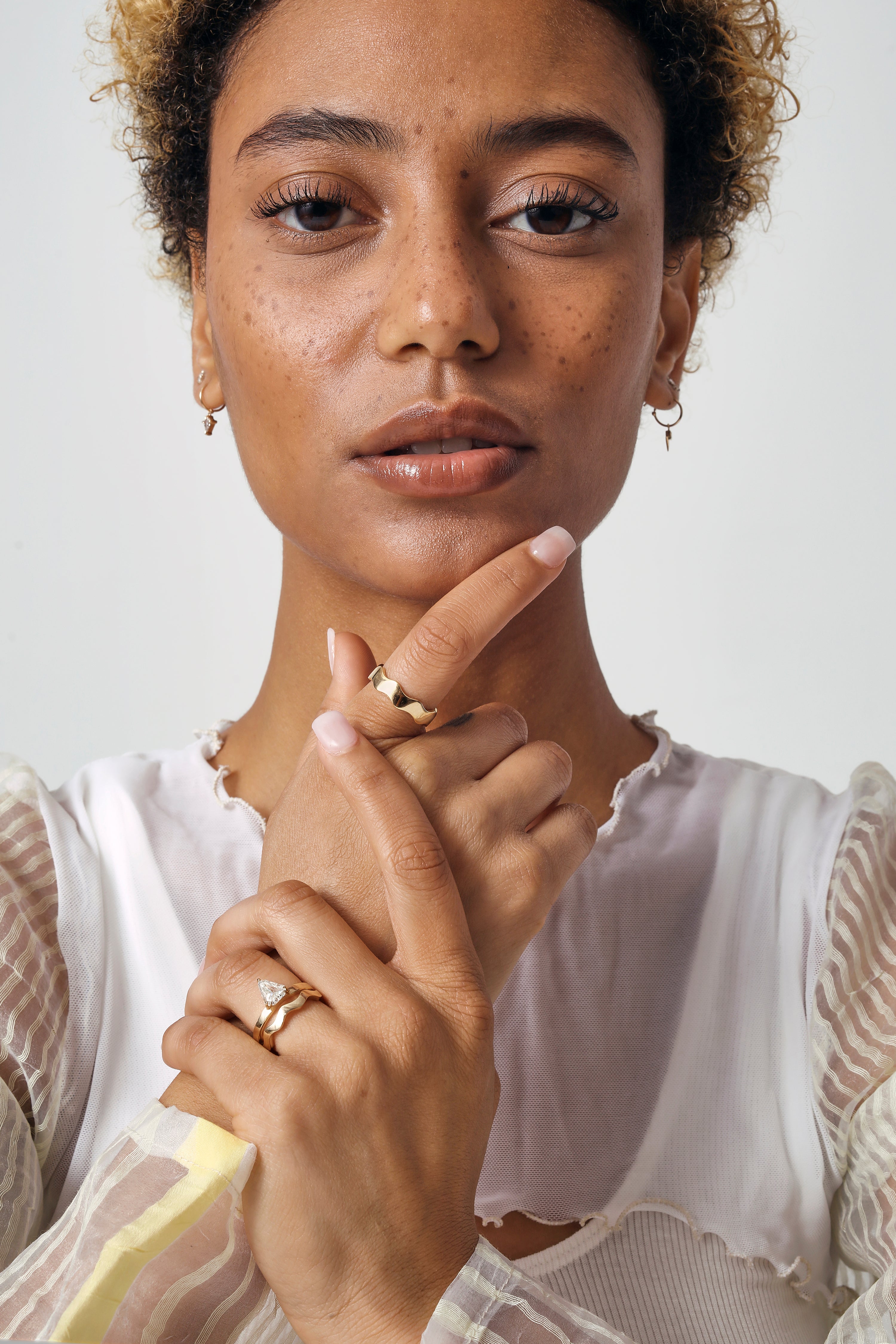 Model wears Waves Band in 14k Yellow Gold stacked with engagement ring on ring finger amongst other Goldpoint pieces