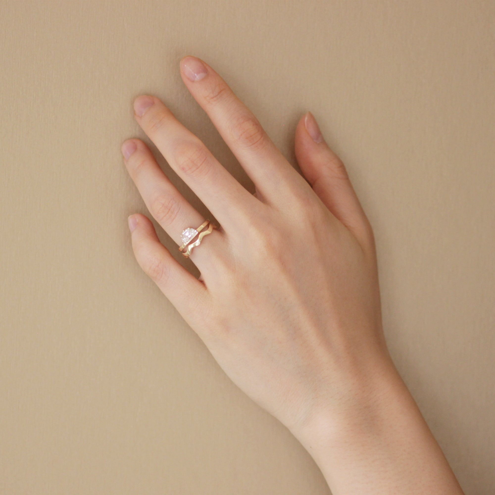 Model wears Waves Band / Thin stacked with an engagement ring on your ring finger by Goldpoint