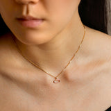 Woman wearing an amorphous circle charm on a gold chain.
